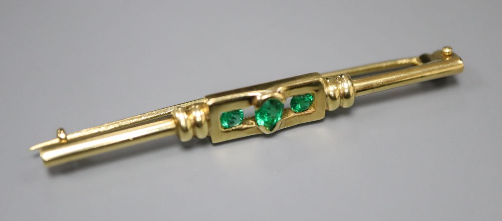 A yellow metal and three stone emerald set tie pin, 52mm, gross 5.4 grams.